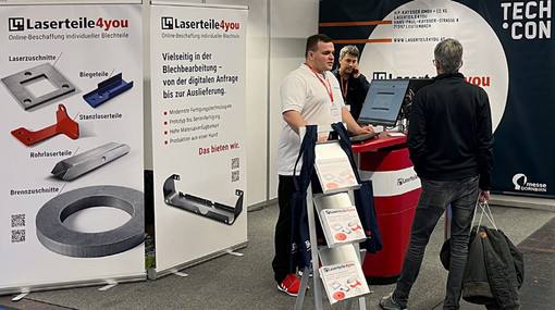 Messebesucher steht am Laserteile4you-Stand und unterhält sich mit Mitarbeiter