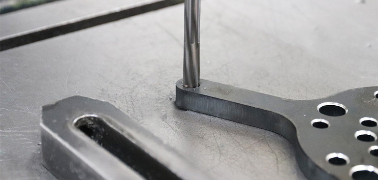 Detailfoto einer Reibahle die in eine Bohrung eines Metallteils bewegt wird