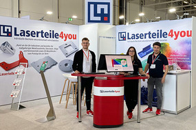 Drei Mitarbeiter von Laserteile4you an einer Theke vor einem Messestand