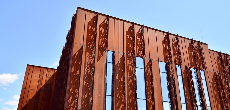 Fassadenkonstruktion aus rostigem Cortenstahl vor blauem Himmel