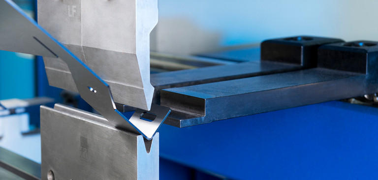 Detailfoto vom Kantwerkzeug einer Kantmaschine, auf der gerade ein Teil gekantet wird.